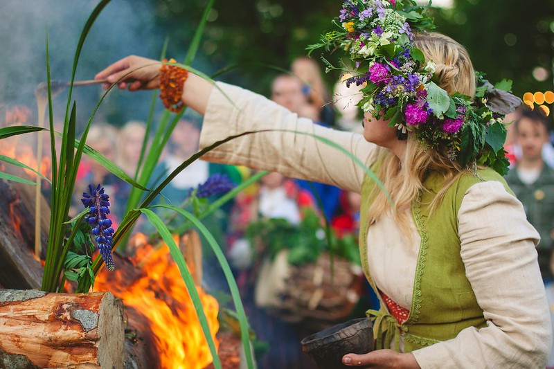woman with floral wreath performs ritual with fire during midsummer in latvia